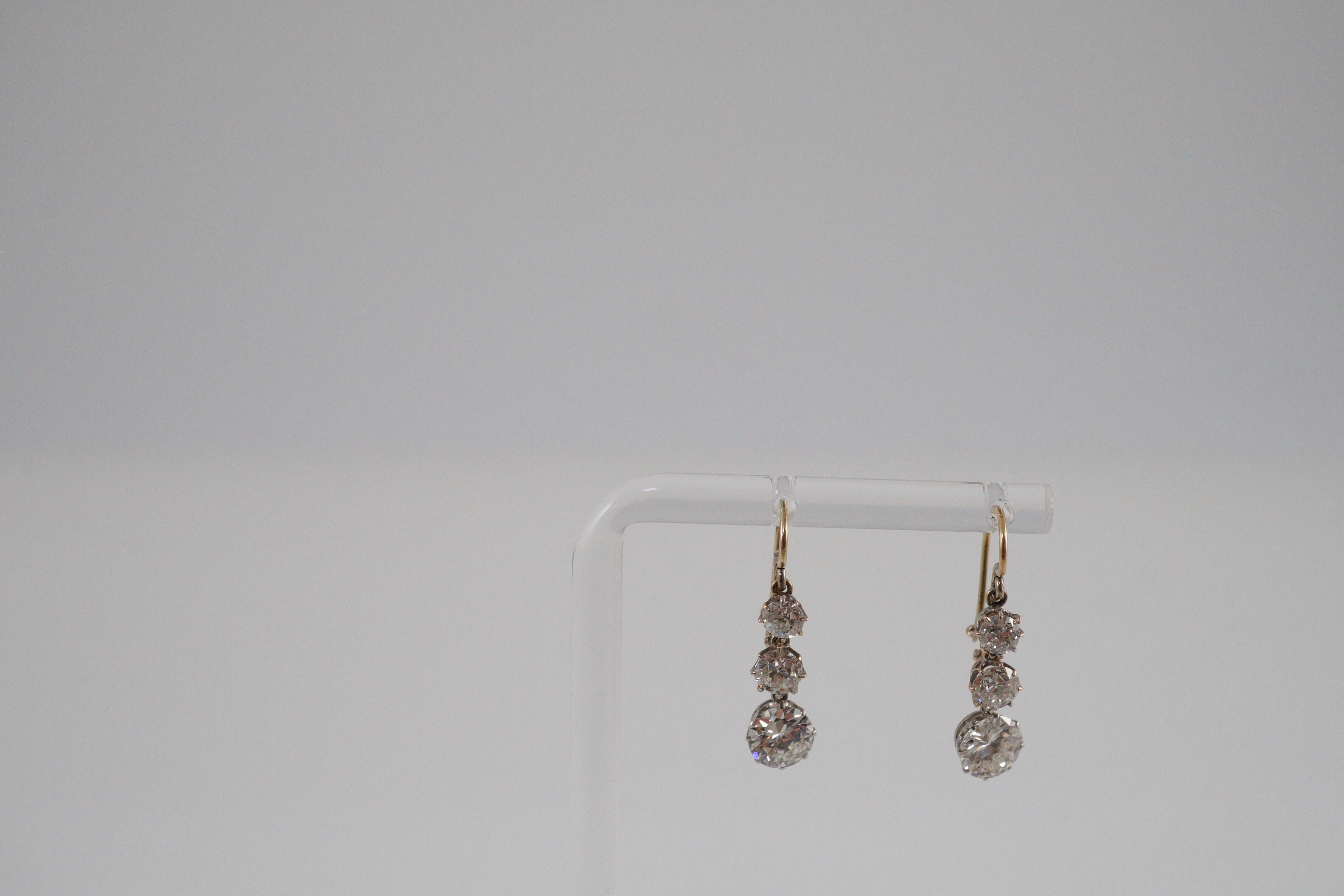 A pair of early to mid 20th century gold, platinum and graduated three stone diamond set drop earrings